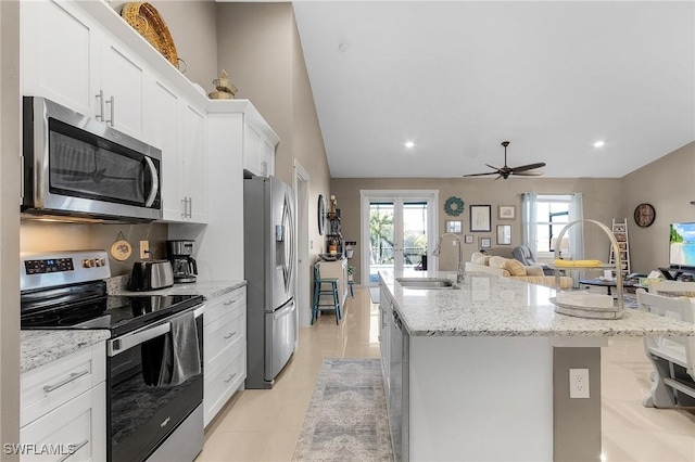 kitchen with white cabinetry, stainless steel appliances, sink, and a center island with sink