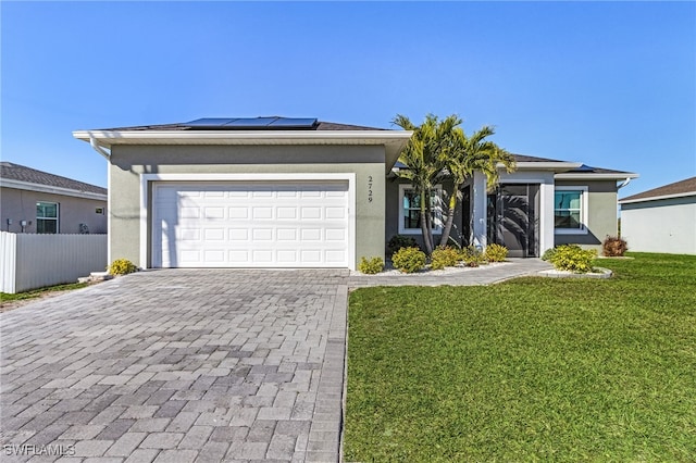 ranch-style home featuring a garage, a front lawn, and solar panels