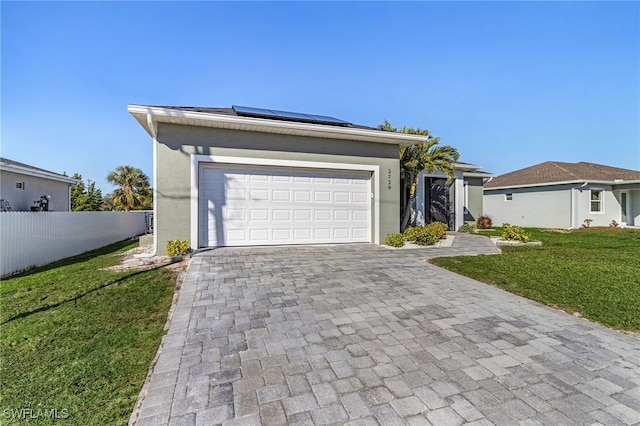 ranch-style home with a garage, a front yard, and solar panels