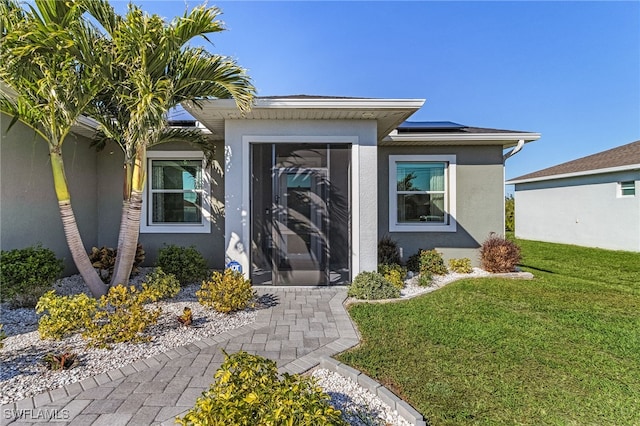 property entrance featuring a yard and solar panels