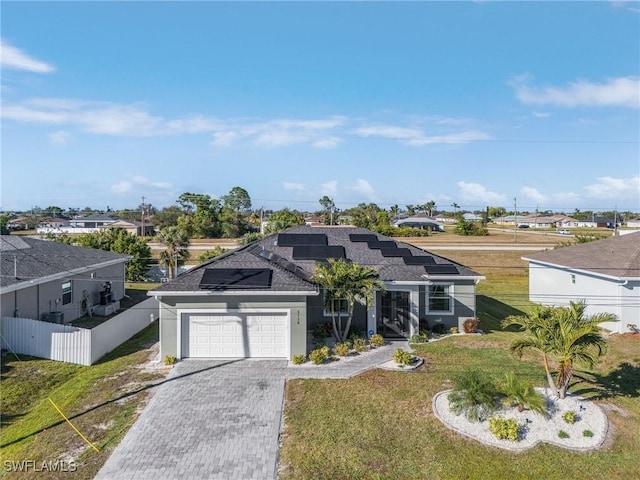 view of front of home with a garage, a front yard, and solar panels