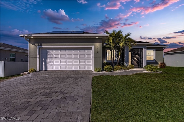 ranch-style house with stucco siding, an attached garage, a lawn, and decorative driveway