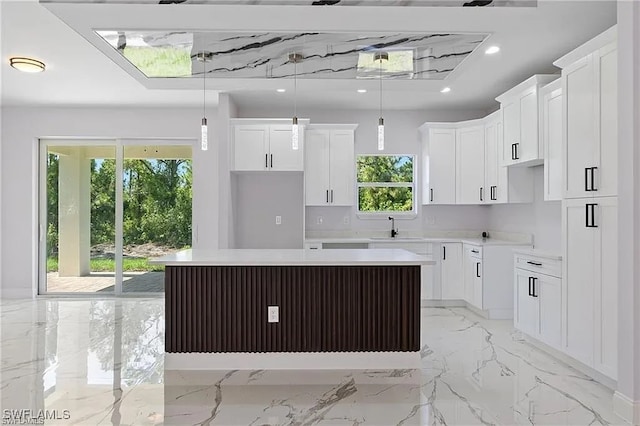 kitchen featuring white cabinetry, a center island, sink, and decorative light fixtures