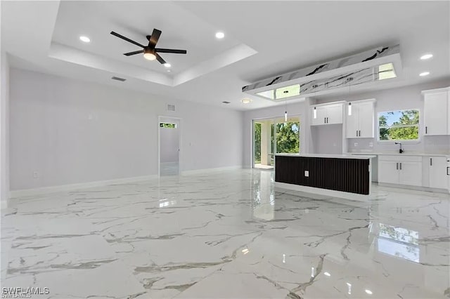 empty room featuring sink, a tray ceiling, and ceiling fan