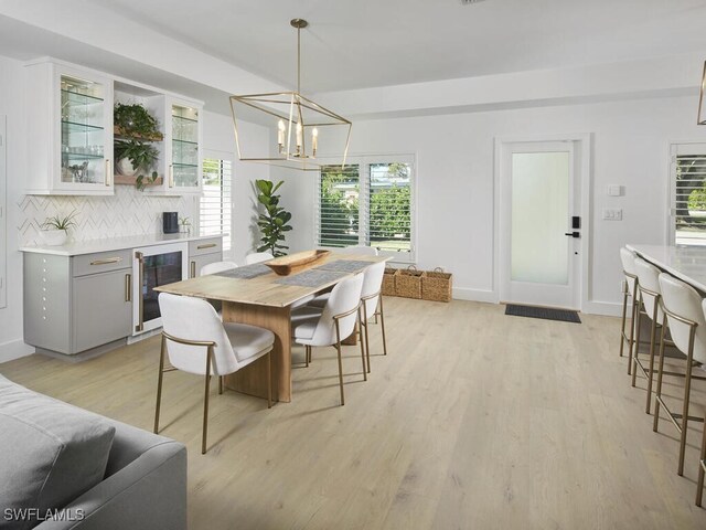 dining room featuring wine cooler, an inviting chandelier, and light wood-type flooring