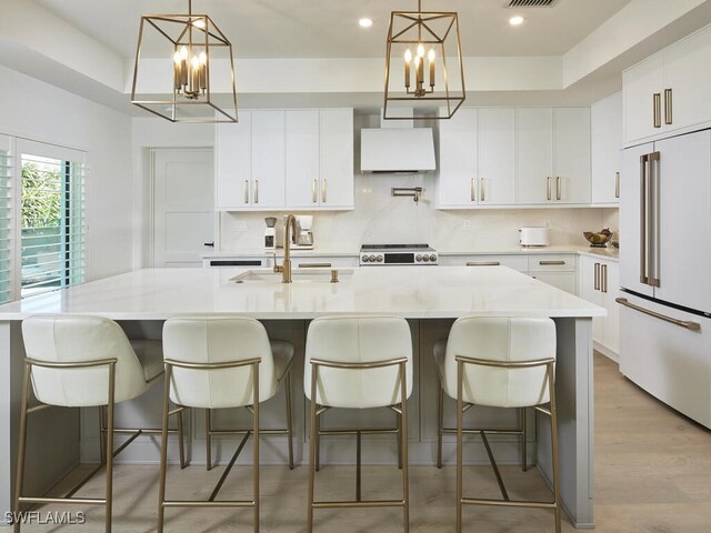 kitchen featuring white cabinetry, a breakfast bar area, hanging light fixtures, paneled built in refrigerator, and a large island