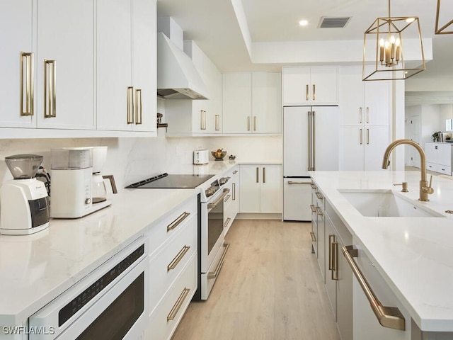 kitchen featuring sink, paneled built in refrigerator, white cabinetry, hanging light fixtures, and white range with electric stovetop