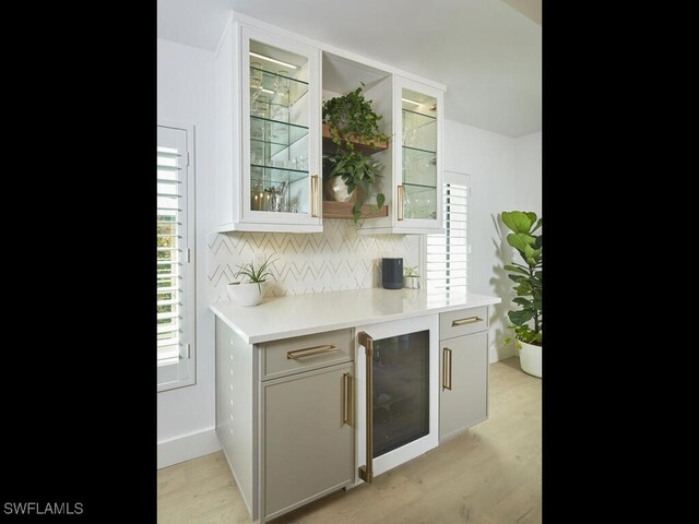 kitchen featuring white cabinetry, beverage cooler, light wood-type flooring, and backsplash