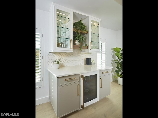 bar with light wood finished floors, tasteful backsplash, and wine cooler