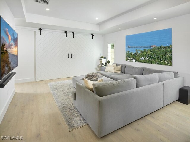 living room with a tray ceiling and light hardwood / wood-style floors