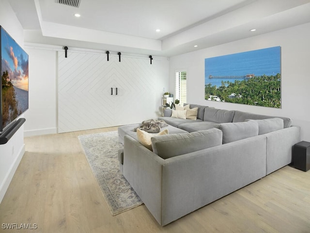 living area featuring recessed lighting, a raised ceiling, visible vents, and light wood-style flooring