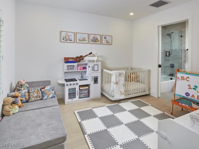 bedroom featuring connected bathroom, recessed lighting, wood finished floors, visible vents, and a crib