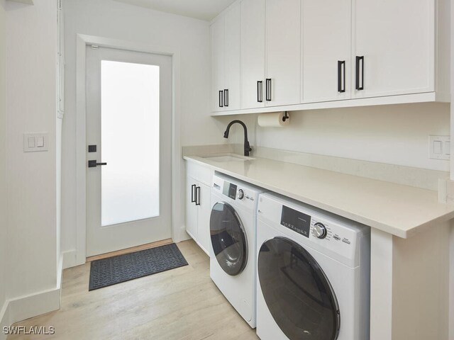 washroom with cabinets, sink, light hardwood / wood-style floors, and washing machine and dryer