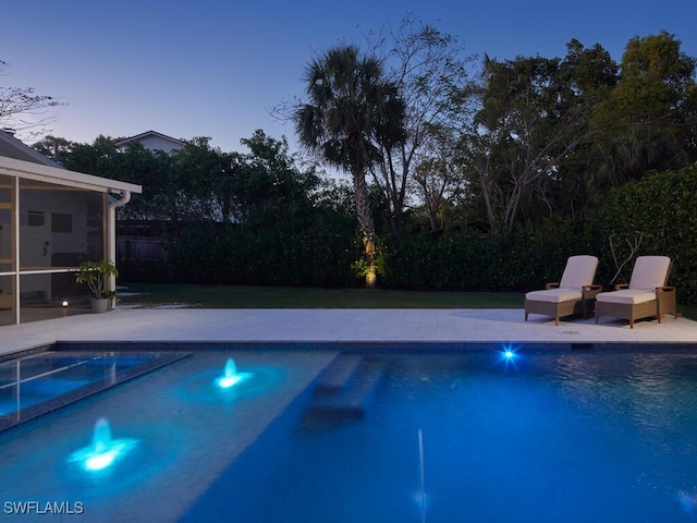 pool at dusk with a pool with connected hot tub and a patio