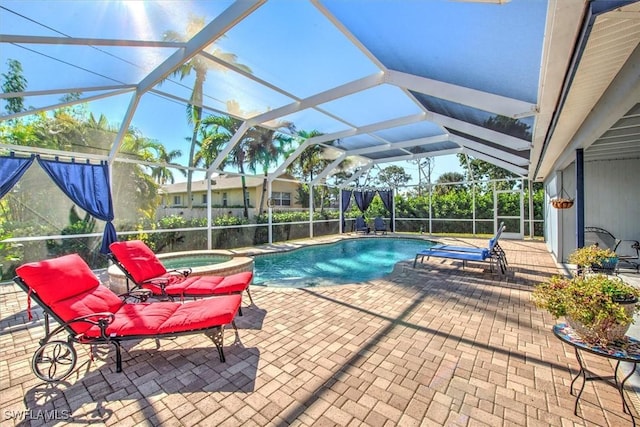 view of pool featuring an in ground hot tub, glass enclosure, and a patio