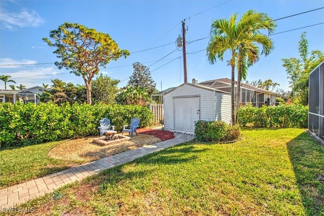 view of yard featuring a storage shed, glass enclosure, and an outdoor fire pit