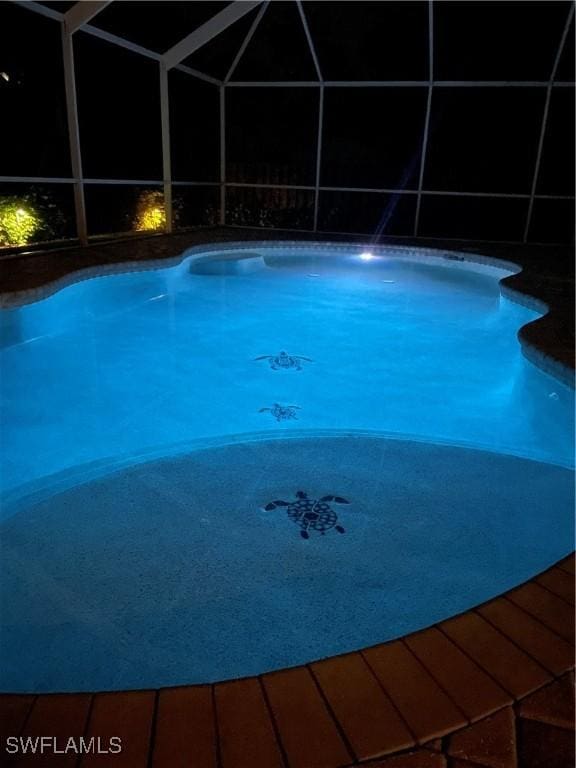 view of swimming pool featuring glass enclosure