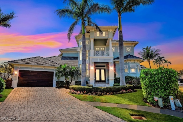 view of front of property with a garage, a lawn, french doors, and a balcony