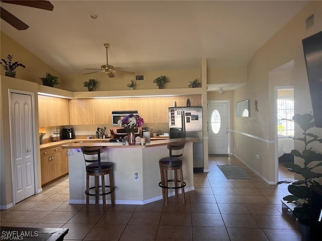 kitchen featuring a center island, stainless steel appliances, a breakfast bar, and lofted ceiling