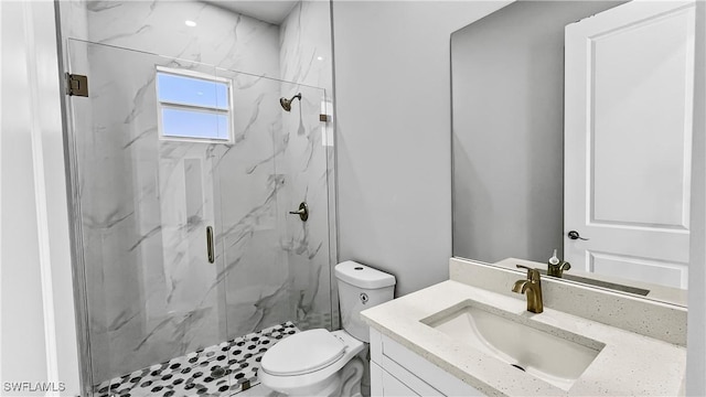 bathroom featuring vanity, a shower with shower door, and toilet