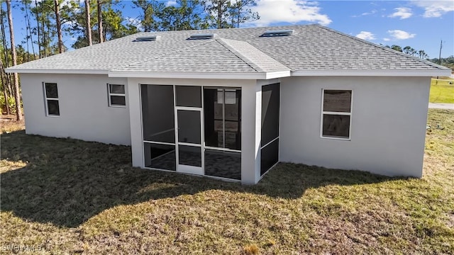 back of property with a sunroom and a lawn