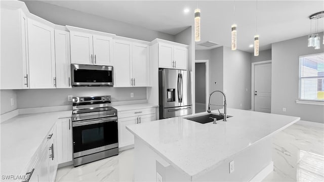 kitchen featuring appliances with stainless steel finishes, white cabinetry, sink, hanging light fixtures, and a kitchen island with sink