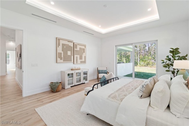 bedroom with a tray ceiling, access to exterior, baseboards, light wood-type flooring, and recessed lighting