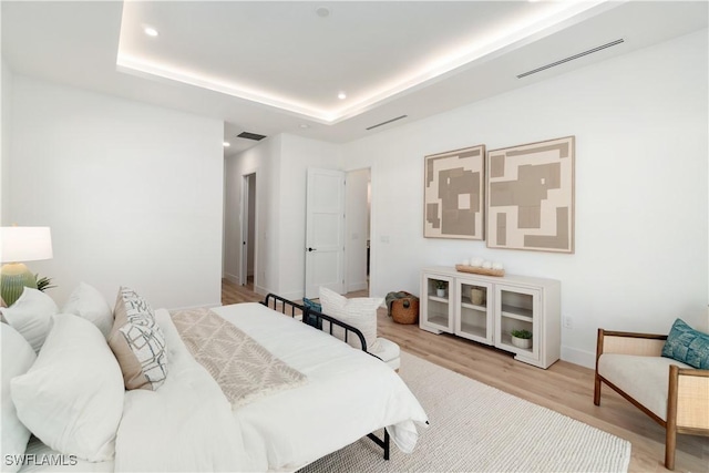 bedroom featuring a raised ceiling and light hardwood / wood-style flooring