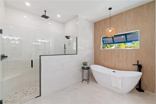 bathroom featuring a shower stall, a freestanding bath, and tile patterned flooring