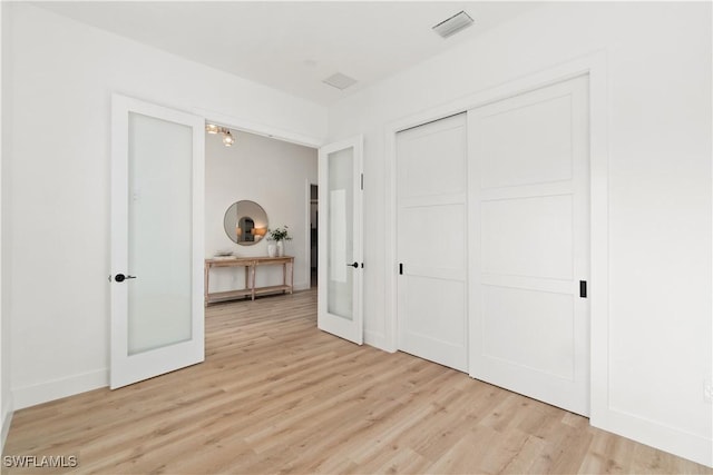 unfurnished bedroom featuring a closet, light wood-type flooring, and french doors