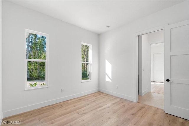 unfurnished room featuring baseboards, light wood-style flooring, and plenty of natural light