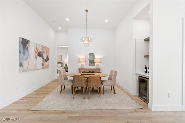 dining room with a towering ceiling, beverage cooler, and light hardwood / wood-style floors