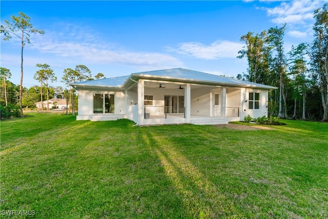 rear view of property with a patio, ceiling fan, stucco siding, and a yard