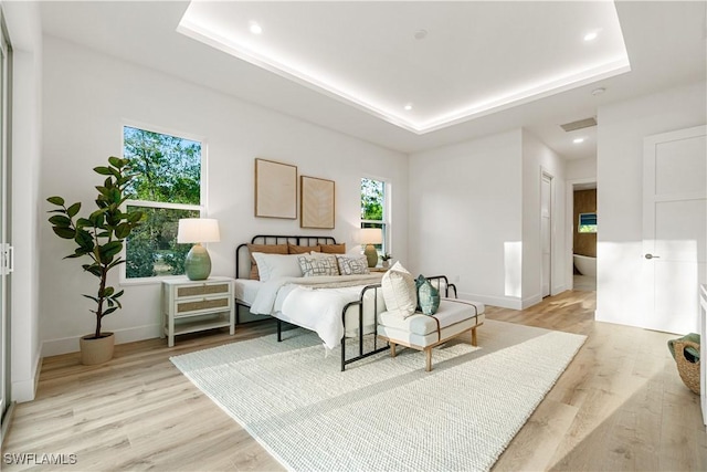 bedroom featuring recessed lighting, baseboards, light wood-style floors, and a tray ceiling