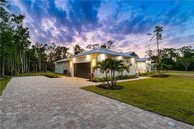 view of front of house featuring metal roof, a front yard, decorative driveway, and an attached garage