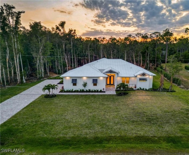 view of front of house with french doors, a yard, and a view of trees