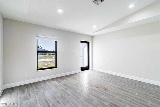 spare room with vaulted ceiling and light hardwood / wood-style flooring