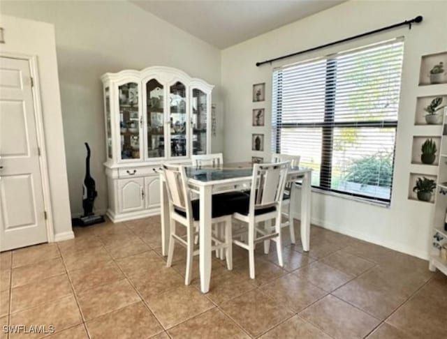 dining area with light tile patterned flooring and vaulted ceiling