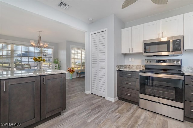 kitchen featuring white cabinetry, appliances with stainless steel finishes, light wood-type flooring, and light stone counters