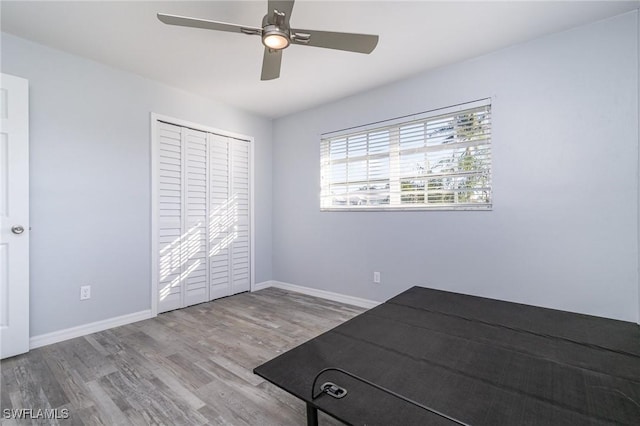 unfurnished bedroom featuring ceiling fan, light hardwood / wood-style floors, and a closet