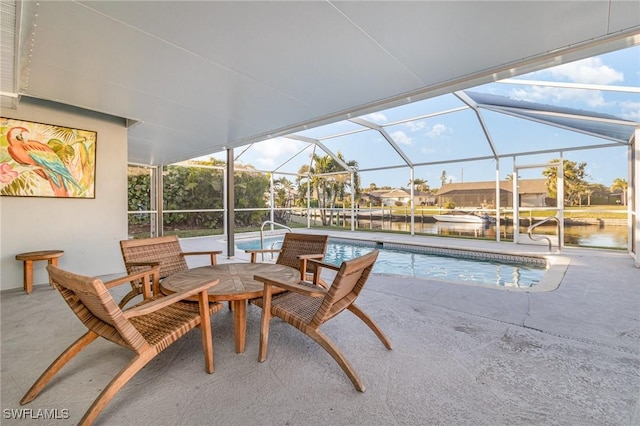 view of pool with a water view, glass enclosure, and a patio area