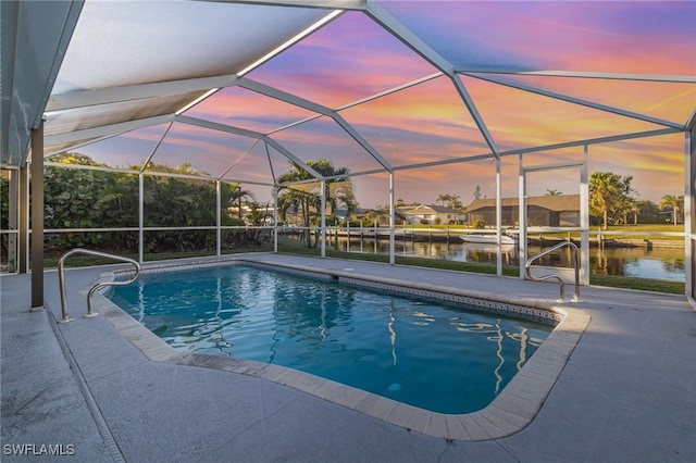 pool at dusk featuring a water view, a patio area, and a lanai