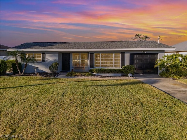 ranch-style home with a garage and a lawn