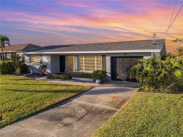 single story home featuring a garage and a lawn