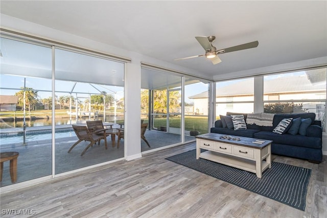 sunroom / solarium featuring a water view and ceiling fan