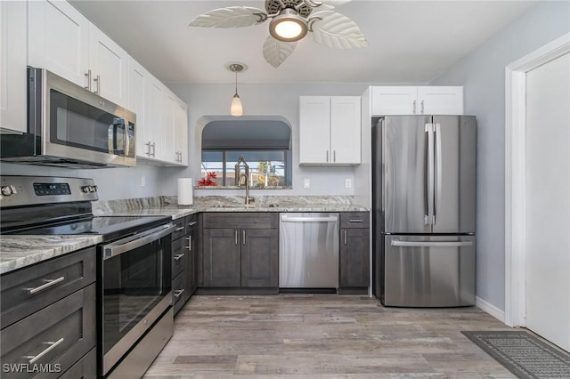 kitchen with appliances with stainless steel finishes, sink, white cabinets, and light stone counters