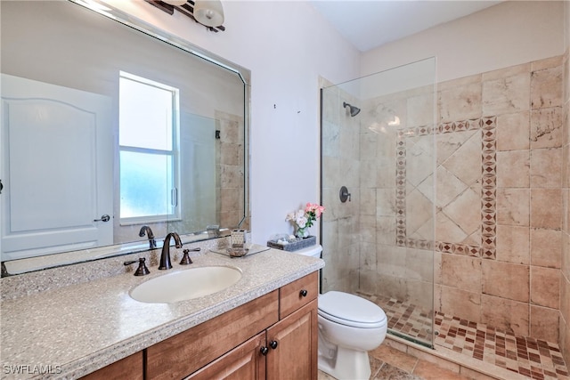 bathroom with vanity, toilet, and a tile shower