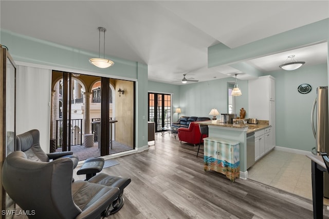 living area featuring baseboards, ceiling fan, and light wood-type flooring