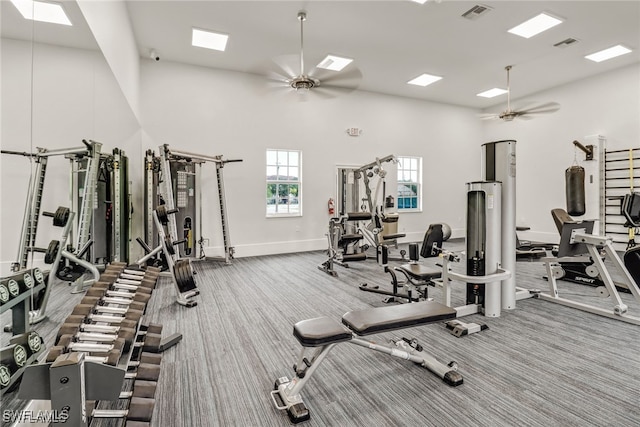 gym featuring carpet floors, ceiling fan, and a high ceiling