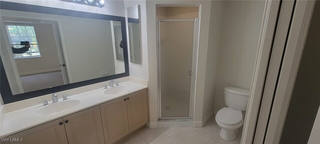 bathroom with toilet, vanity, a shower with door, and tile patterned flooring